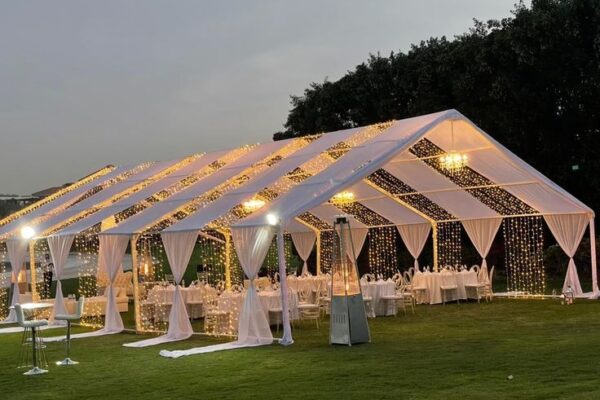 a tent with lights and tables on grass